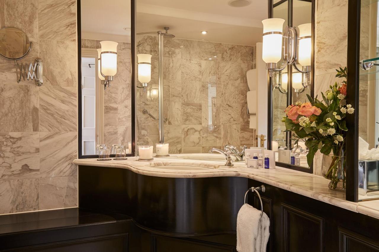 Macdonald Bath Spa Hotel Zewnętrze zdjęcie The photo shows a luxurious bathroom featuring elegant design elements. There is a curved marble countertop with a sink, complemented by stylish silver fixtures. The walls are adorned with light-colored marble, creating a sophisticated ambiance. Seve