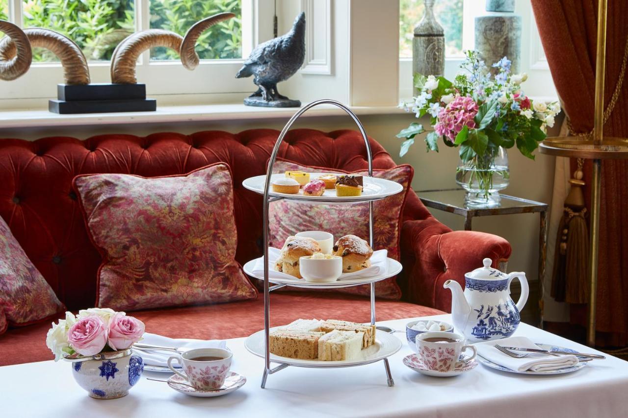 Macdonald Bath Spa Hotel Zewnętrze zdjęcie The photo showcases an elegant afternoon tea setting. In the foreground, there is a three-tiered serving stand filled with various pastries and scones, including some topped with cream and fruit. Surrounding the stand is a beautifully arranged table 