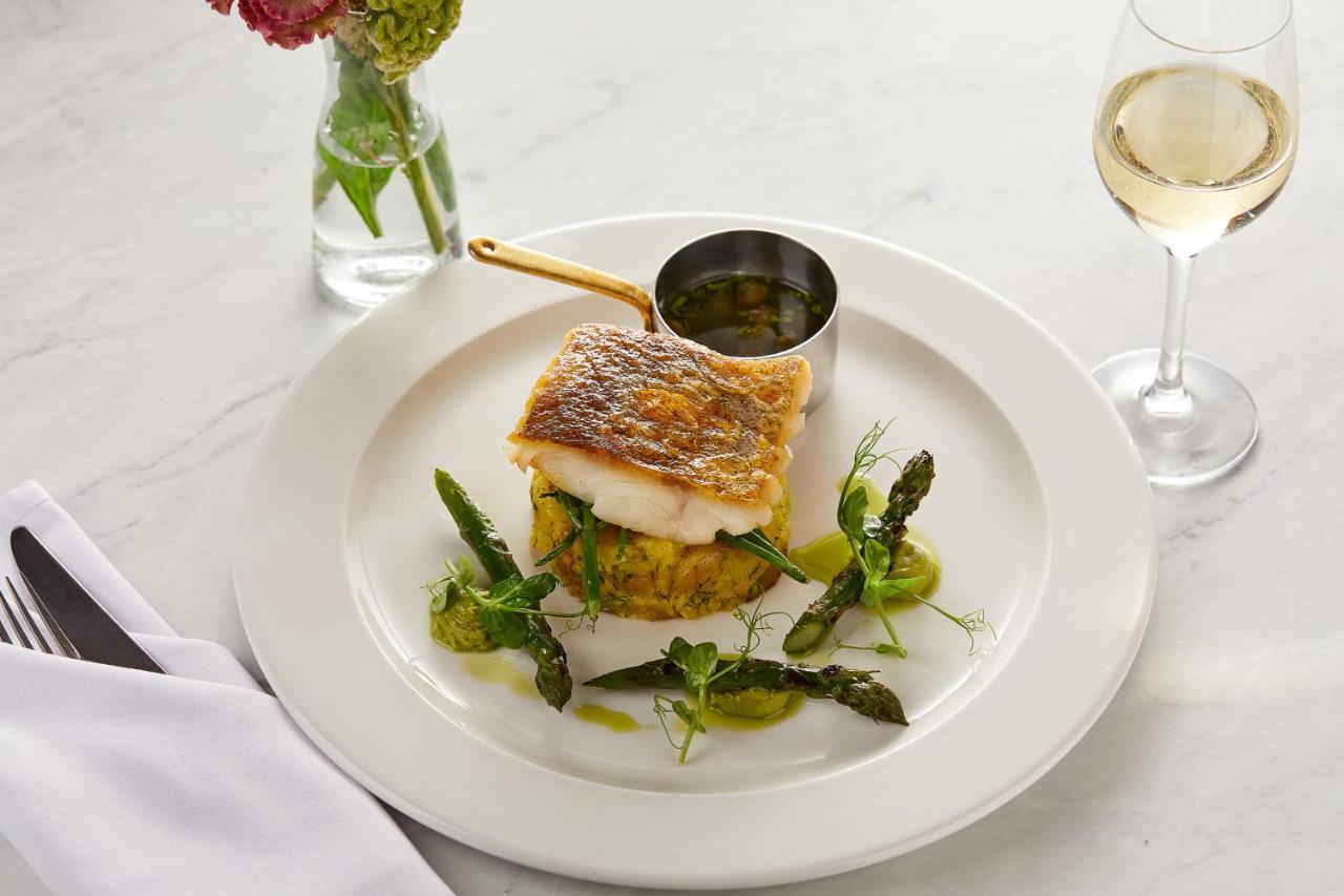 Macdonald Bath Spa Hotel Zewnętrze zdjęcie The photo showcases a beautifully plated dish featuring a piece of fish, likely with a crispy skin, resting on a bed of what appears to be a savory cake or puree. Surrounding the fish are fresh asparagus and garnishes, adding a touch of color and fre