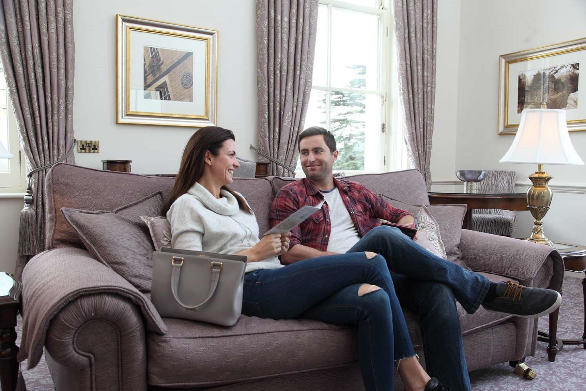 Macdonald Bath Spa Hotel Zewnętrze zdjęcie The photo shows a man and a woman sitting together on a comfortable sofa in a well-decorated room. The woman is holding a piece of paper and appears to be engaged in conversation with the man, who is smiling in response. They are both dressed casuall