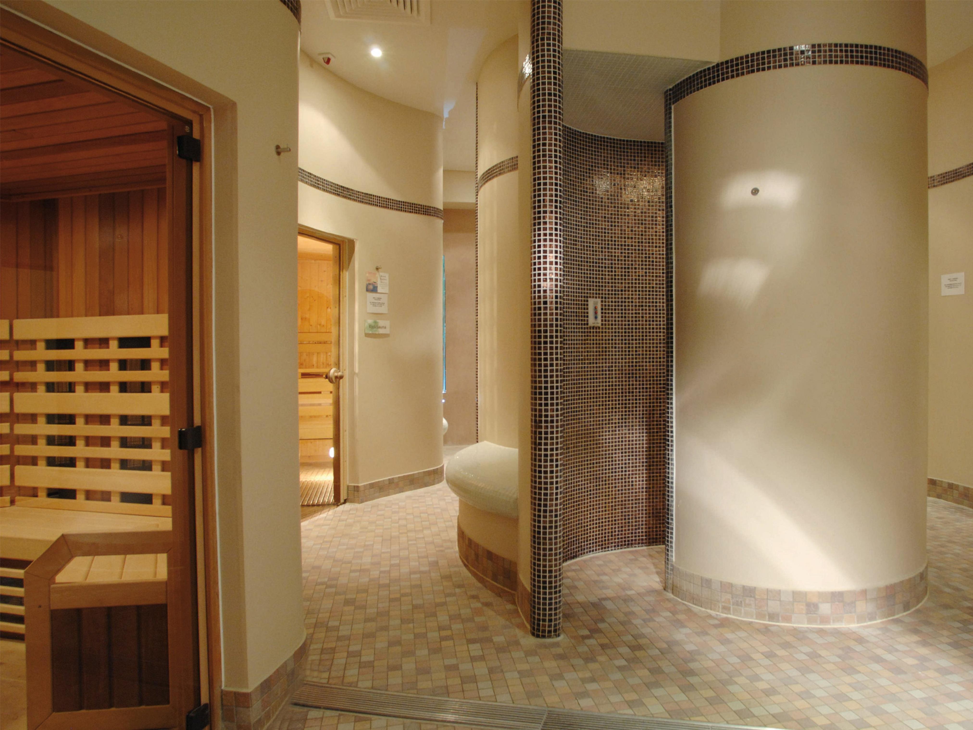 Macdonald Bath Spa Hotel Zewnętrze zdjęcie The photo shows a contemporary spa area featuring a sauna and relaxation space. The interior has smooth, rounded walls and tiled surfaces, creating a calming atmosphere. On one side, there's a wooden sauna with slatted seating. Nearby, a curved wall 