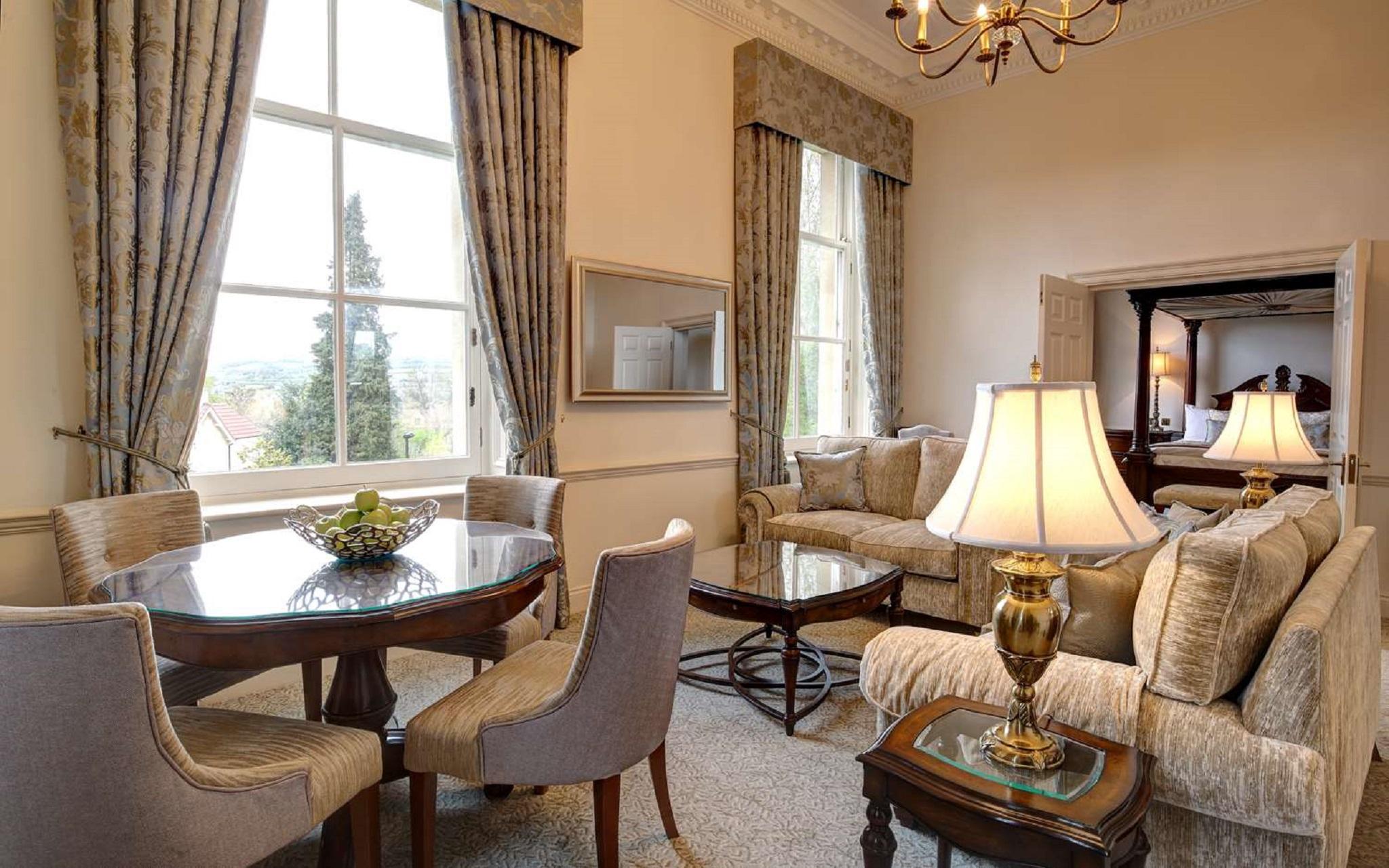 Macdonald Bath Spa Hotel Zewnętrze zdjęcie The photo displays a beautifully furnished living room. The room features large windows dressed with elegant curtains that allow natural light to flood in. There is a comfortable seating area with a stylish sofa and chairs arranged around a small cof