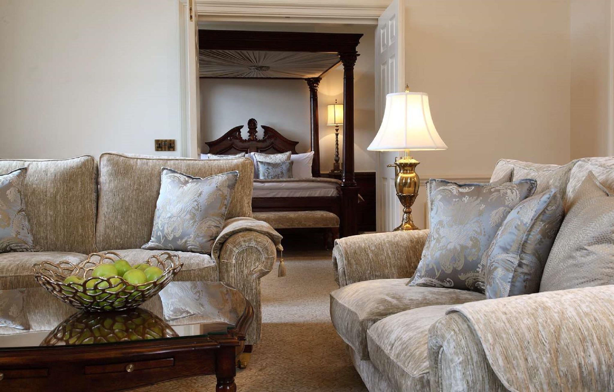 Macdonald Bath Spa Hotel Zewnętrze zdjęcie The photo shows a cozy living space with elegant furnishings. On the left, there is a sofa with plush cushions and a stylish armchair, both in a soft, light-colored fabric. In the center, there is a decorative glass table with a bowl containing what 
