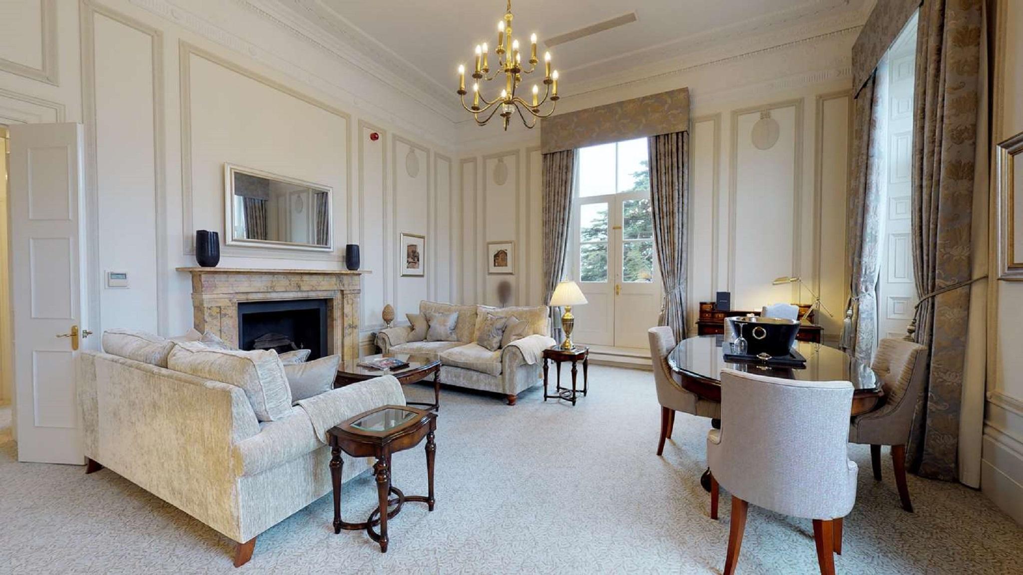 Macdonald Bath Spa Hotel Zewnętrze zdjęcie The photo shows an elegant living room with a classic design. It features a large chandelier hanging from the ceiling, providing soft lighting. The walls are adorned with decorative moldings and have a light color. 

In the center, there are two plus