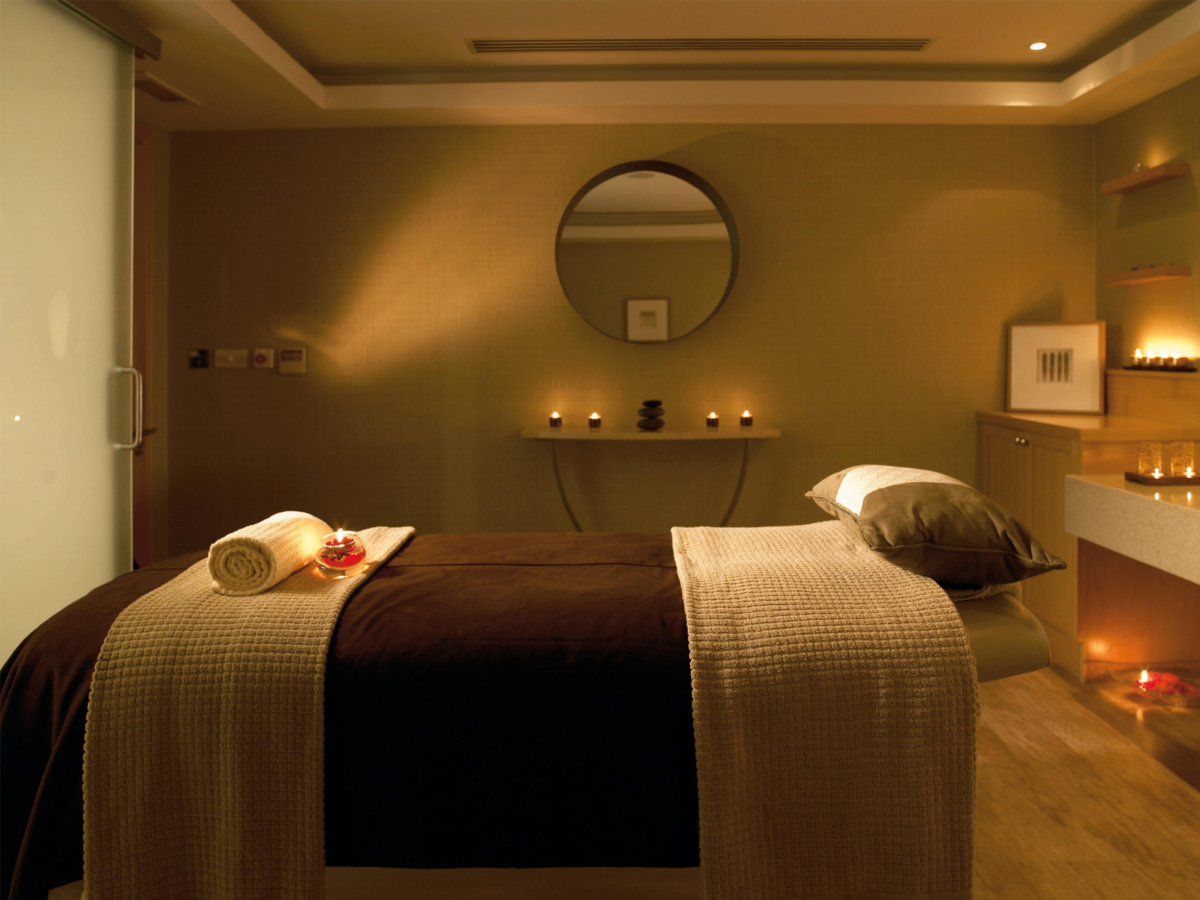 Macdonald Bath Spa Hotel Zewnętrze zdjęcie The photo shows a serene spa room designed for relaxation and wellness. A comfortable massage table is centered in the room, covered with a soft, neutral-toned blanket. On the table, there is a rolled towel and a few decorative elements, possibly flo