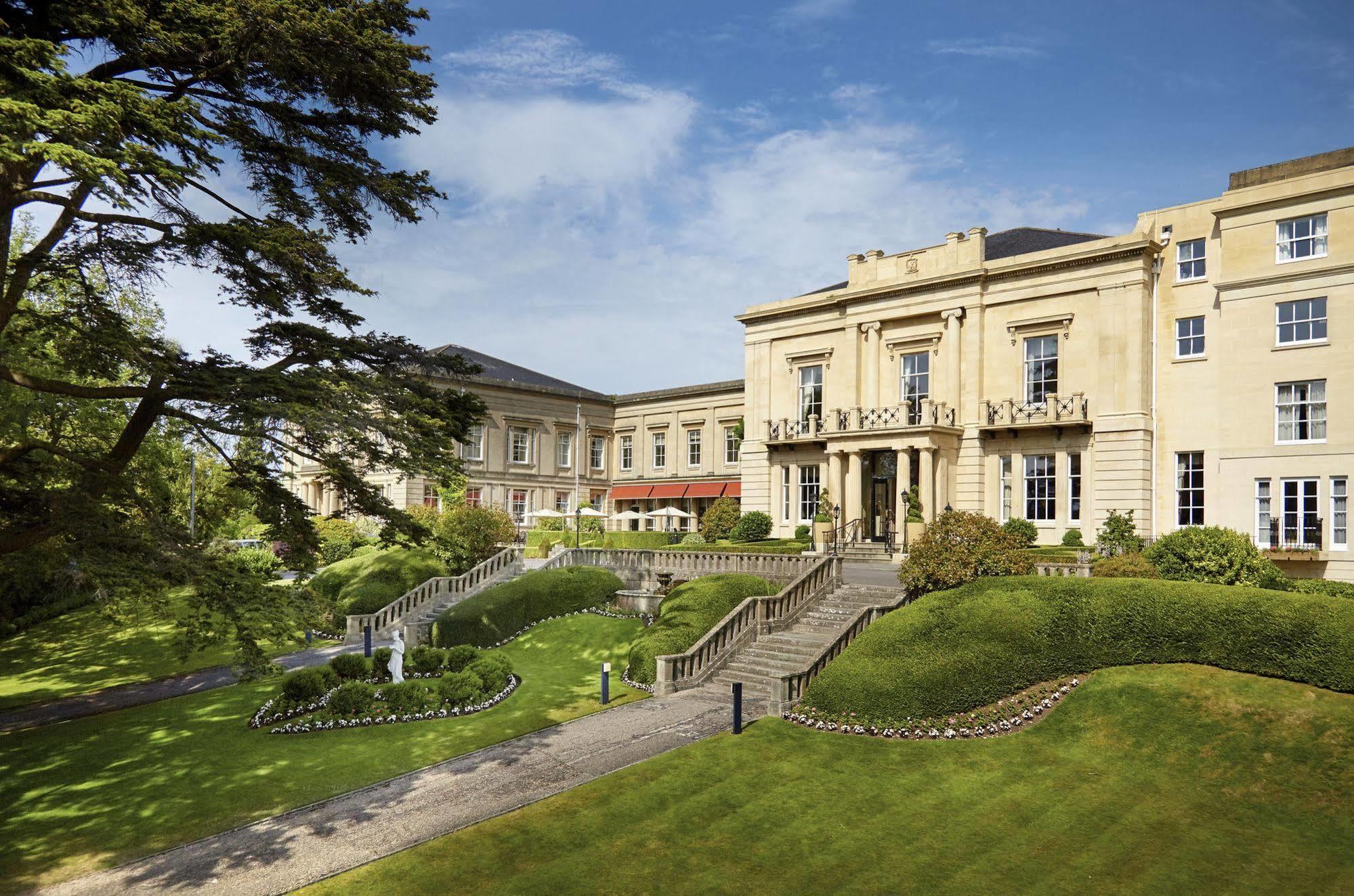 Macdonald Bath Spa Hotel Zewnętrze zdjęcie The photo shows a grand building, likely a hotel or estate, surrounded by well-manicured gardens and lawns. The architecture appears elegant, with multiple stories and large windows. There are steps leading up to the entrance, and the setting include