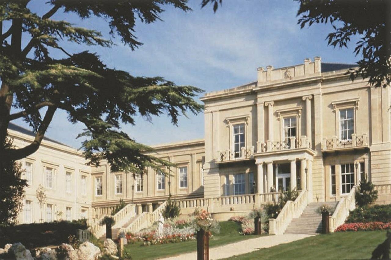 Macdonald Bath Spa Hotel Zewnętrze zdjęcie The photo depicts an elegant, stately building characterized by classical architecture. It features a symmetrical facade with large windows and decorative balconies. The structure is complemented by a lush green lawn and landscaped gardens, enhancing